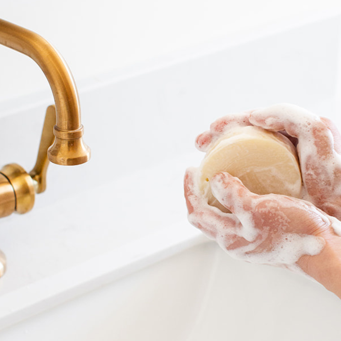 Handcrafted natural bar soap beside a bottle of body wash comparing the benefits of each for healthy skin.