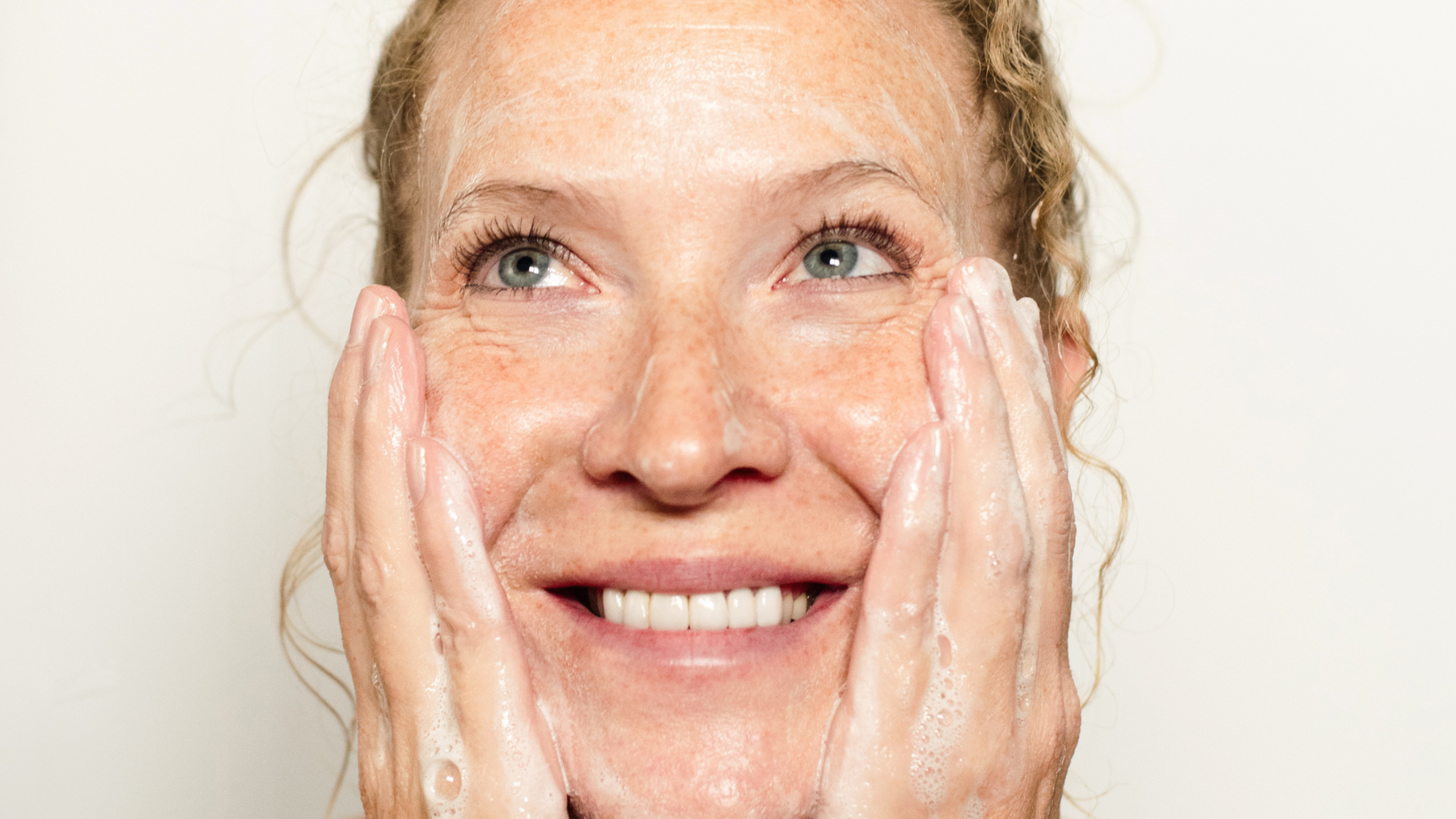 Woman cleansing her face with a natural cold process bar soap beside Wild Prairie Soap Company facial-friendly soap bars.