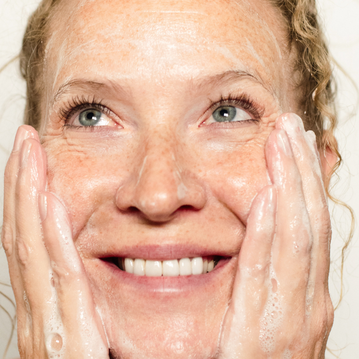 Woman cleansing her face with a natural cold process bar soap beside Wild Prairie Soap Company facial-friendly soap bars.