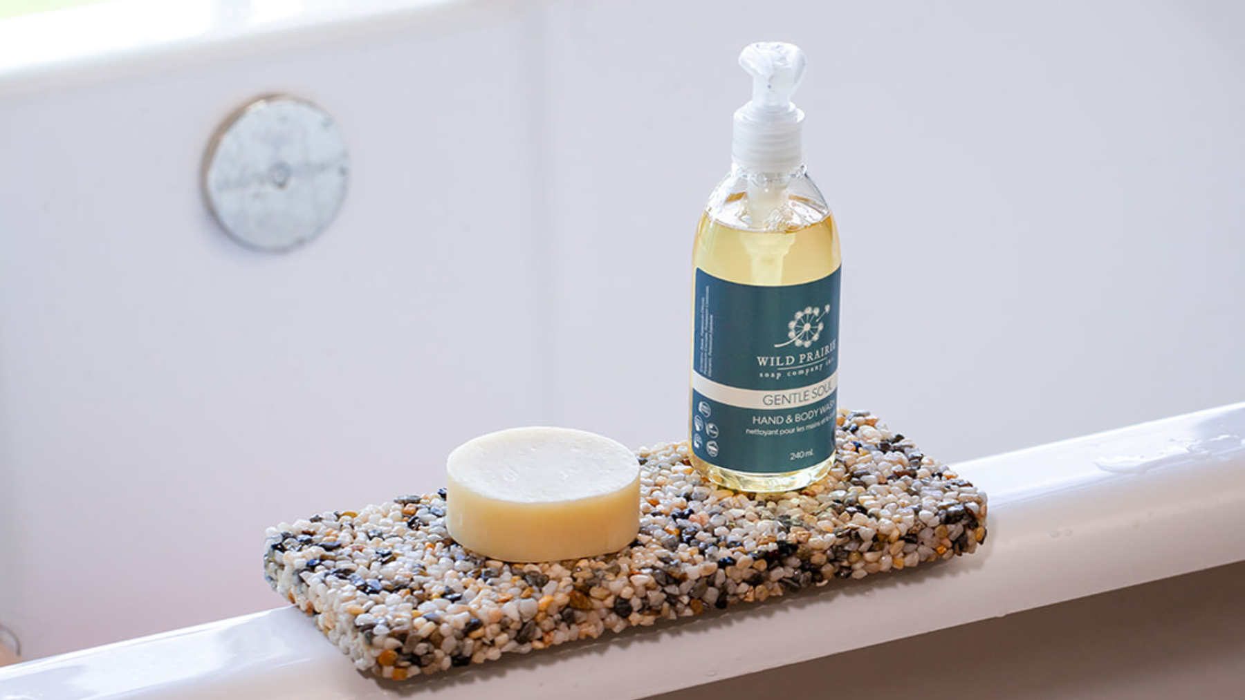 Handmade bar soap resting on a Wild Prairie stone soap plate beside a bathroom sink