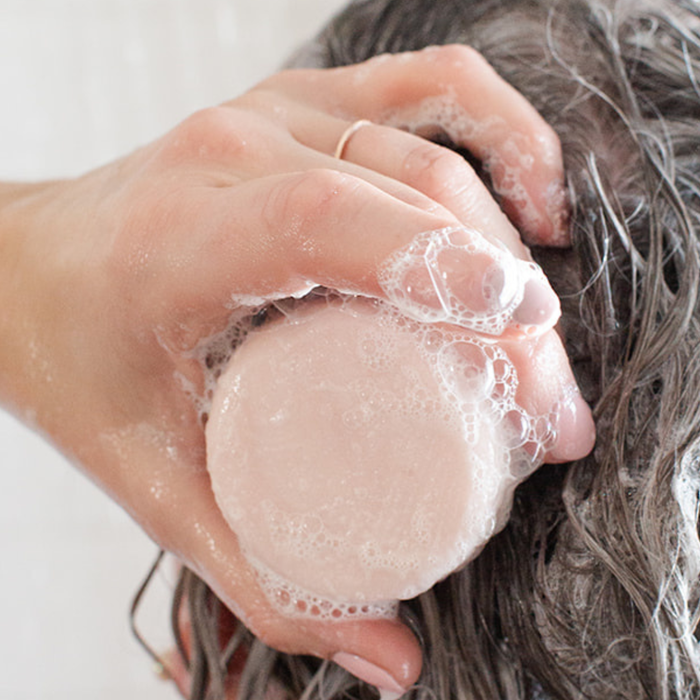 Wild Prairie natural shampoo and conditioner bars stored on a draining stone soap dish to extend lifespan